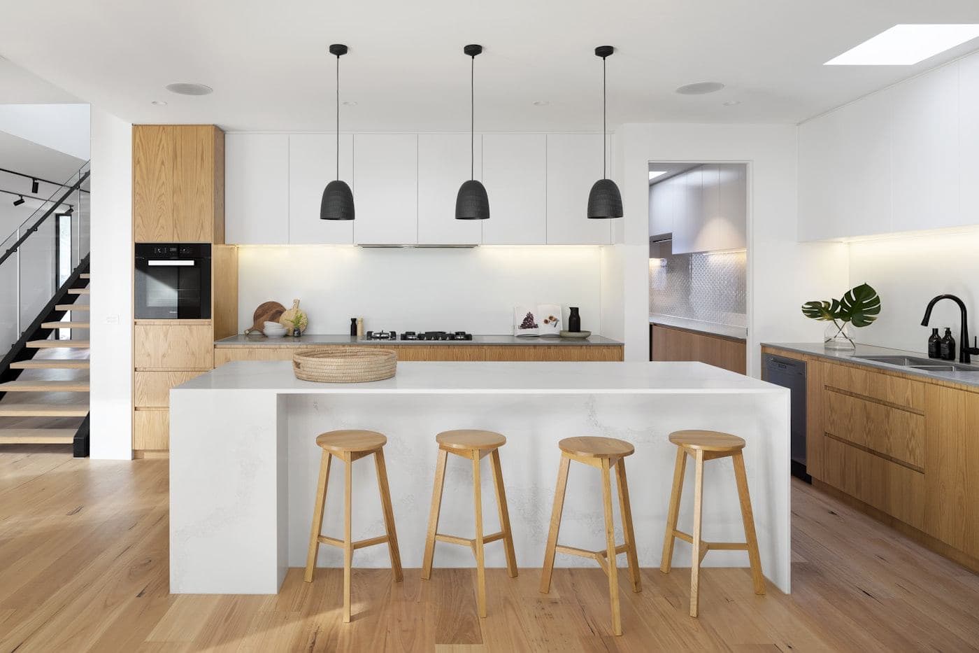 Kitchen with a white stone island and timber stools