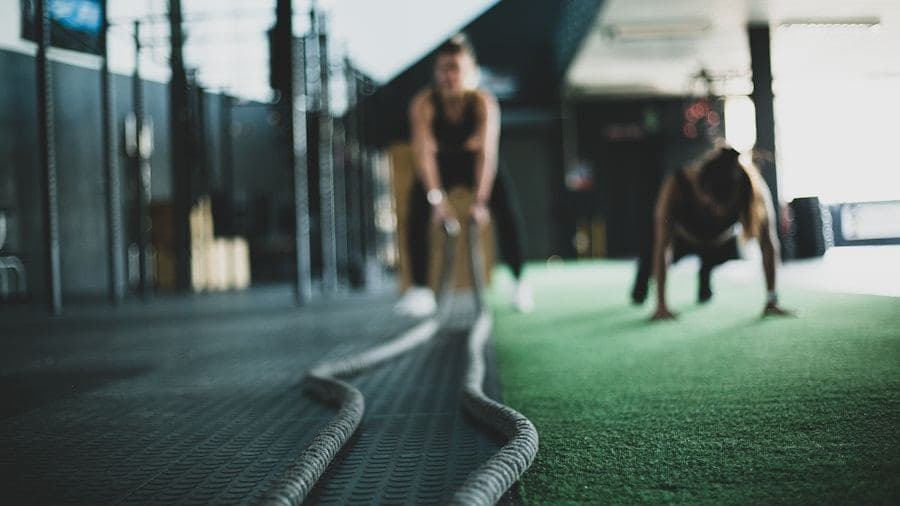 Athlete working battle ropes on gym turf
