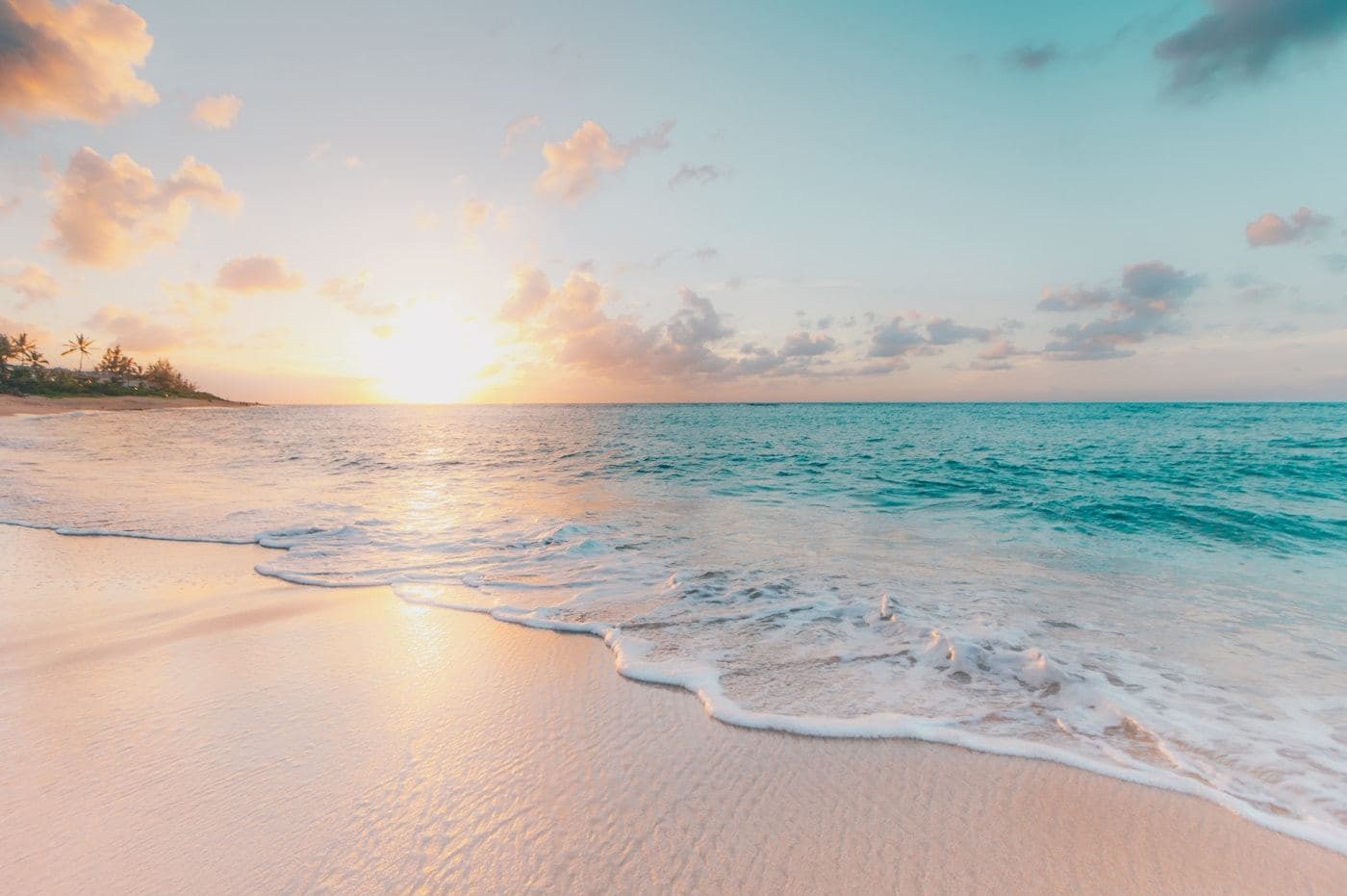 Quiet white-sand beach at sunset with gentle surf