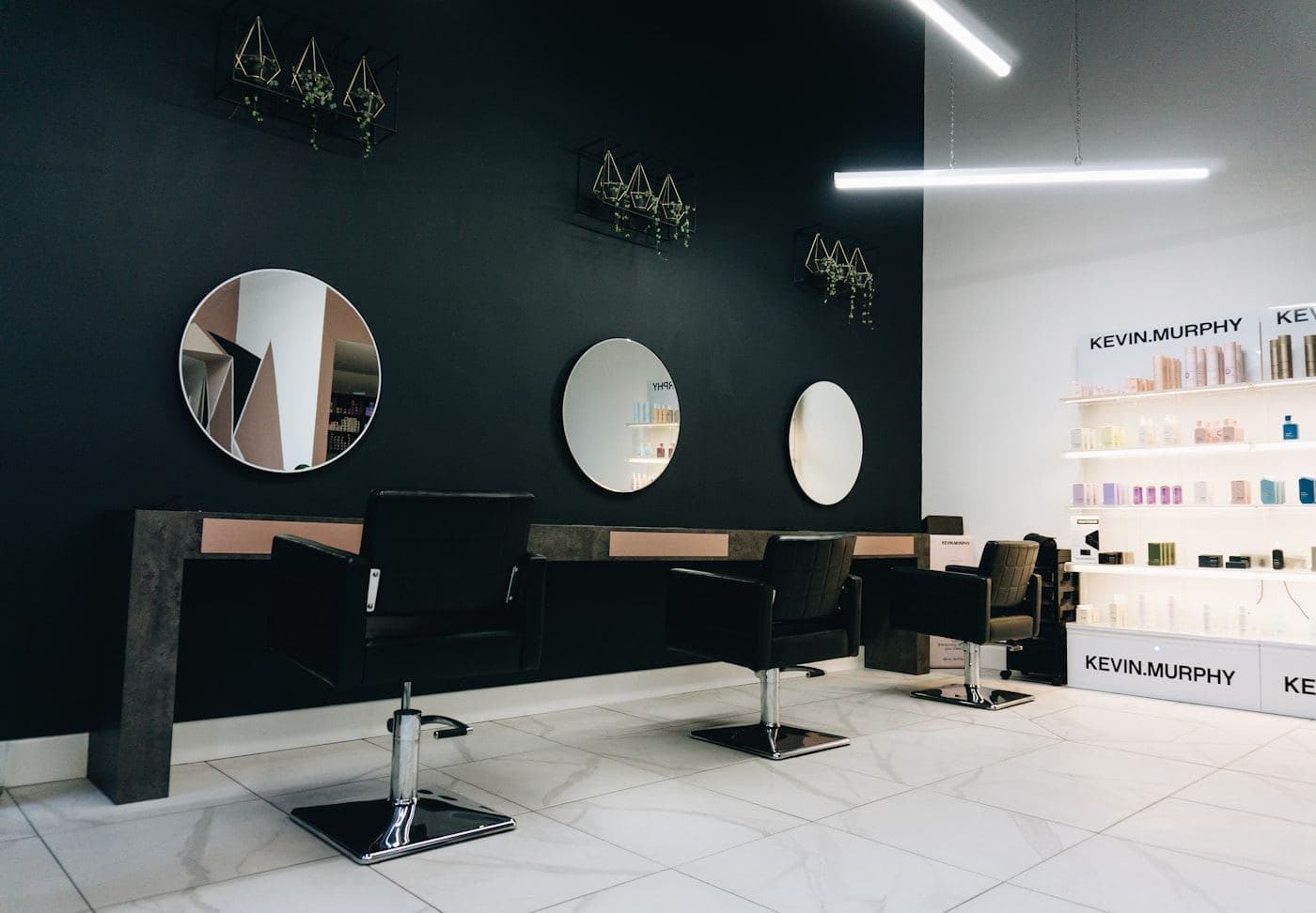 Salon styling stations with round mirrors on a dark wall