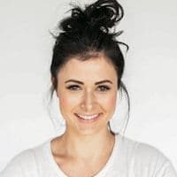 Smiling woman with dark hair tied up, wearing a white t-shirt
