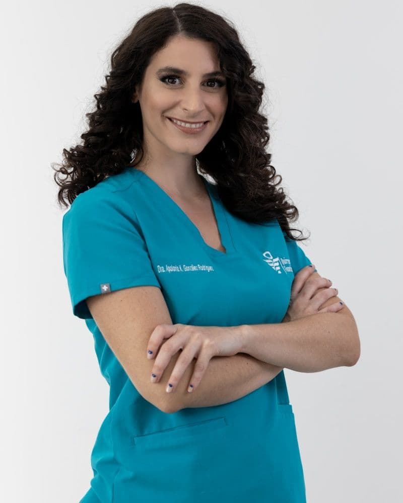 Clinician in teal scrubs standing with her arms folded, smiling