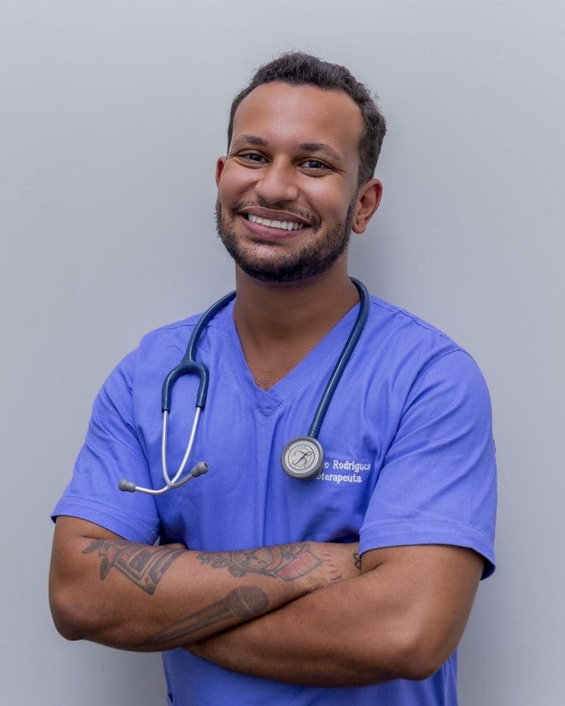Smiling clinician in blue scrubs with arms folded
