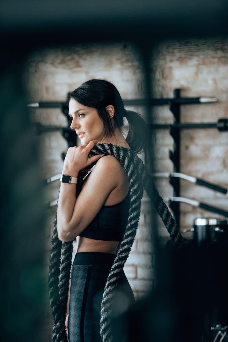 Coach mid-set with a battle rope in a dark gym