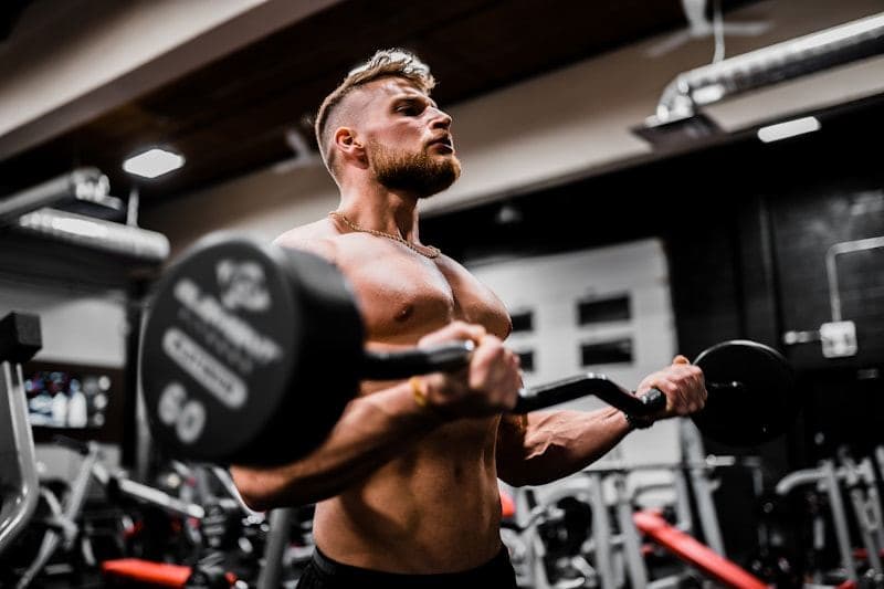Coach curling a heavy dumbbell in a dark gym