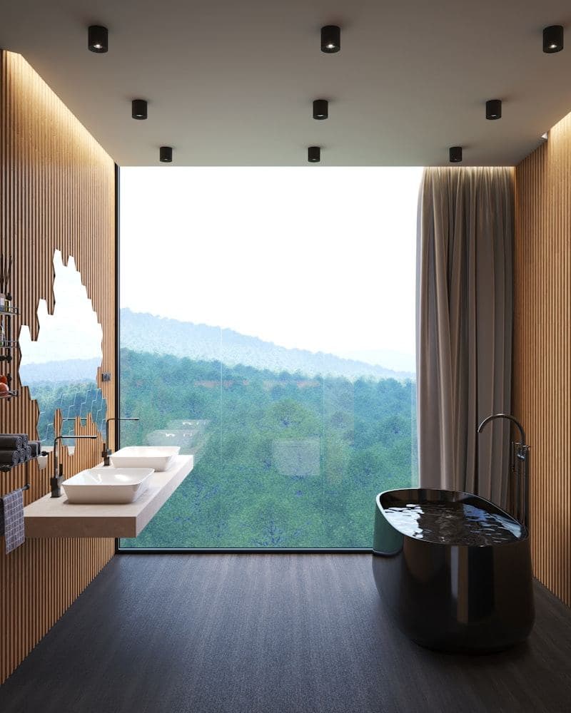 Marble bathroom with a freestanding tub beside a tall window